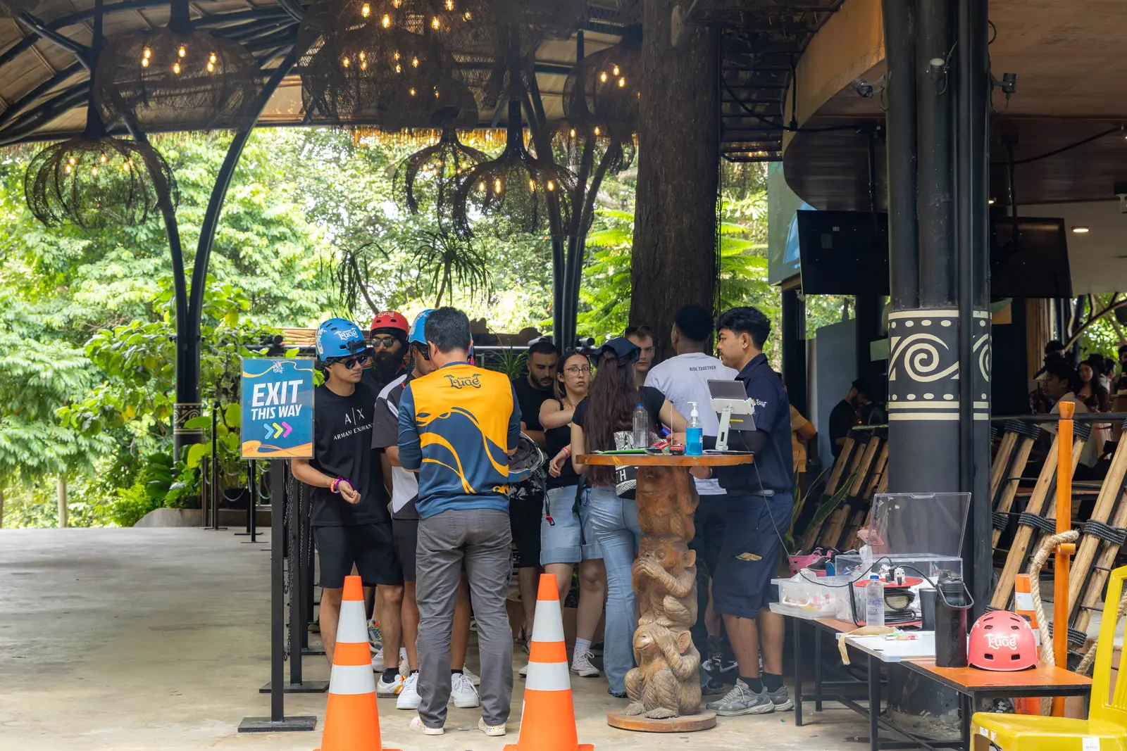 Visitors wearing helmets beside the Hanuman Luge team in the covered arrival area.